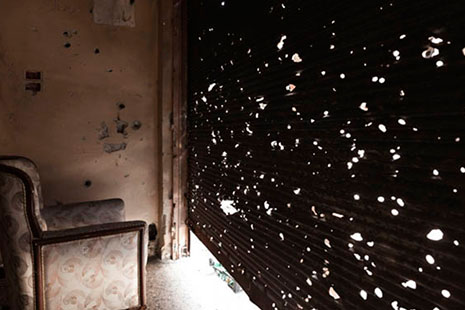 Sillón tapizado frente a una puerta de persiana ligeramente abierta. Fotografía de Carole Alfarah