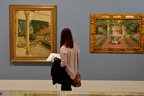 Una mujer de espaldas frente a dos cuadros de Sorolla