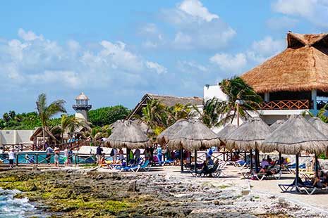 Qué época es mejor para viajar a cada continente playa de México Vista de la playa con sombrillas de paja en Cozumel, México