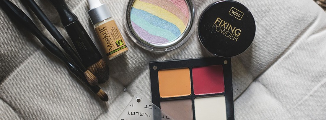 Productos de maquillaje encima de un sillón blanco