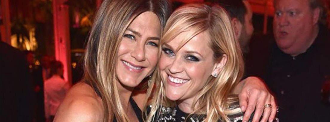 Jennifer Aniston y Reese Witherspoon en Apple TV actrices Jennifer Aniston sonriente pasa su mano por el hombro de Reese Witherspoon
