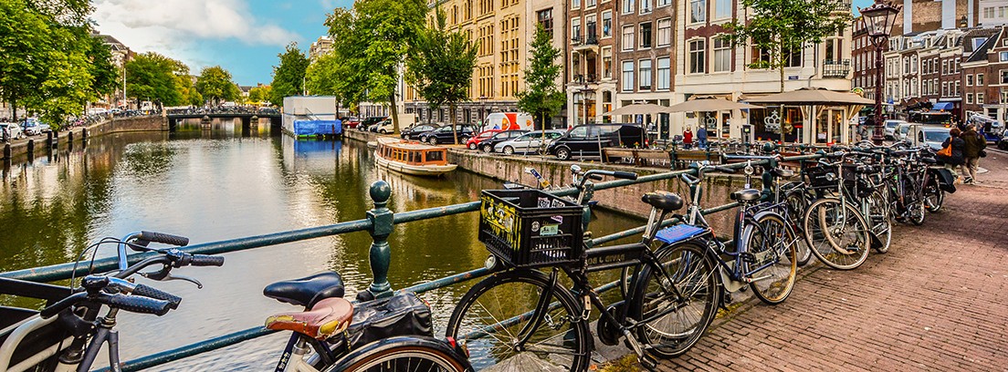 mejores ciudades para ir en bici Amsterdam Vista de un canal de Ámsterdam, Holanda, con bicis aparcadas