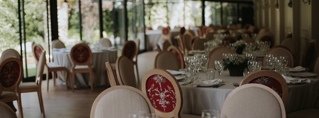 Diferentes mesas redondas con copas, platos y manteles blancos