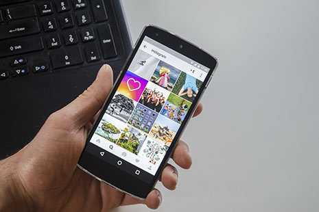 Cómo recuperar fotos de Instagram Mano sujetando un móvil con la pantalla de Instagram
