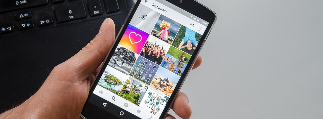 Cómo recuperar fotos de Instagram Mano sujetando un móvil con la pantalla de Instagram