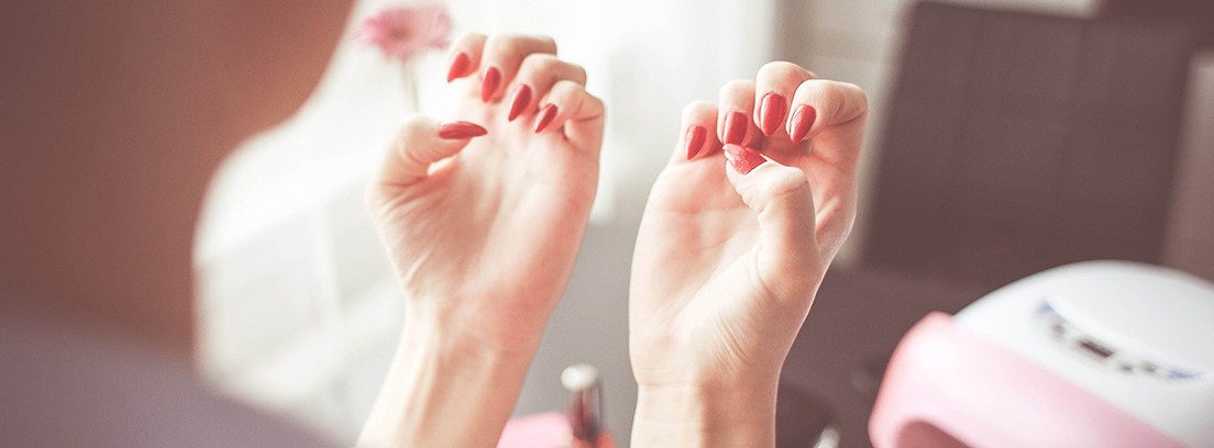 Manicura permanente para verano Mujer de espaldas mirando sus uñas rojas