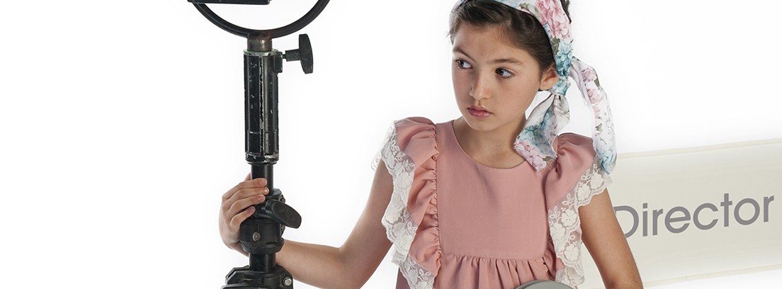 Niña sujetando un cinta de cine y un foco con vestido de José Verón