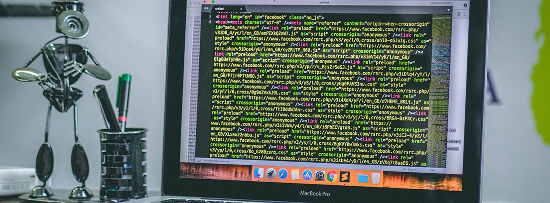 Ordenador portátil con pantalla con código escrito en amarillo y junto a robot metálico