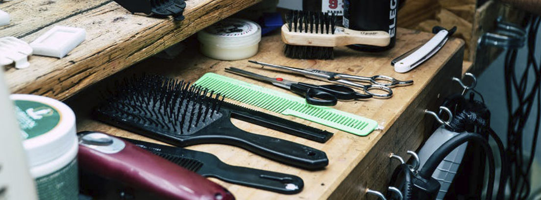 Estante de madera con varios peines y cepillos sobre él.