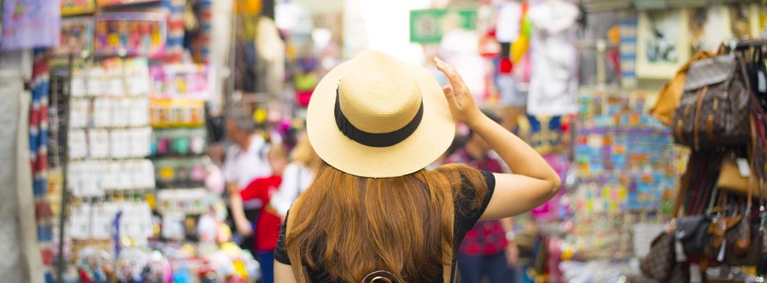 Madrid, una de las ciudades más turísticas de España Mujer con mochila marrón y sombrero caminando de espaldas por una calle de Mongkok en Hong Kong