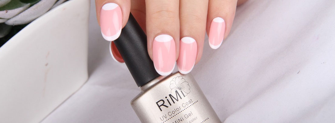 Mano con las uñas pintadas de rosa y un bote de esmalte de uñas