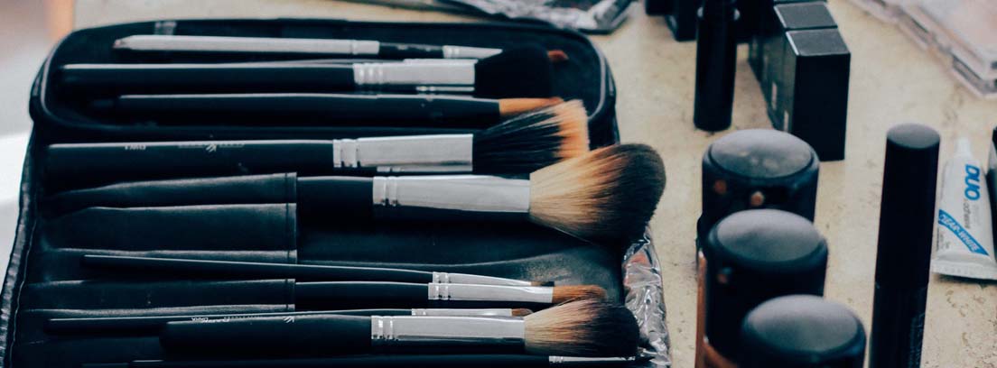 Diferentes brochas de maquillaje en funda negra y junto a botes