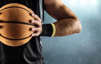 Un jugador de baloncesto vestido de negro sostiene un balón entre sus manos