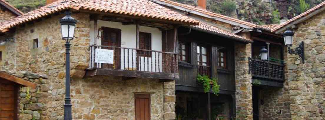 pueblos más bonitos del norte de españa Casas de piedra y madera junto a farola negra y delante de colina verde