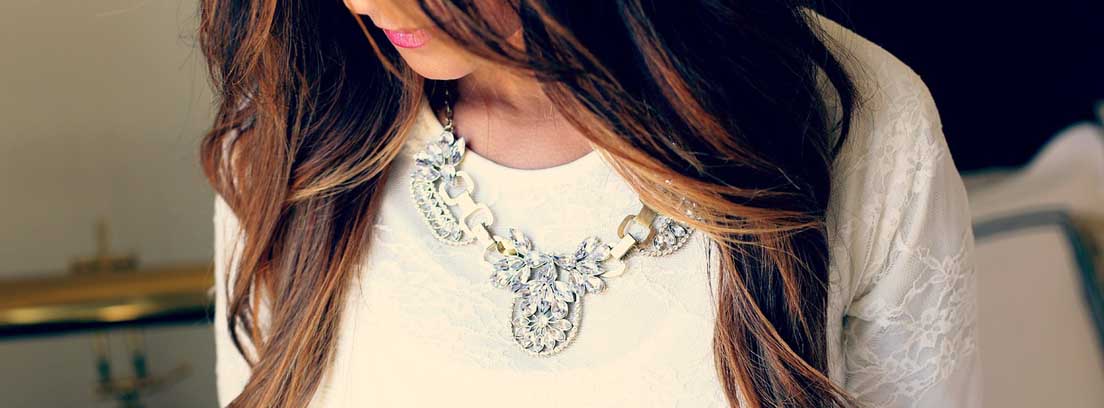 Complementos para fiesta Mujer con collar como complemento de fiesta sobre vestido blanco