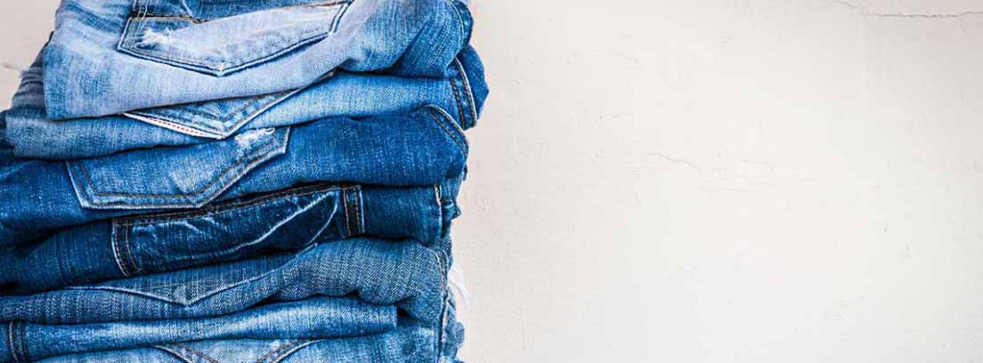 Armarios de ropa básicos como los pantalones vaqueros Montón de pantalones vaqueros doblados sobre una superficie de madera