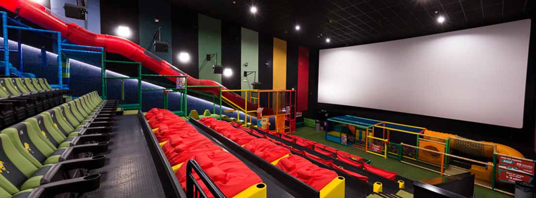Las salas junior de cine con tobogán Salas junior de cine con butacas verdes y rojas y tobogán en forma de tubo.