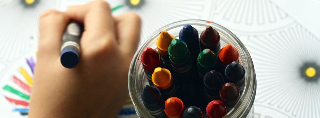 Mano con pintura junto a bote de pinturas de colores.