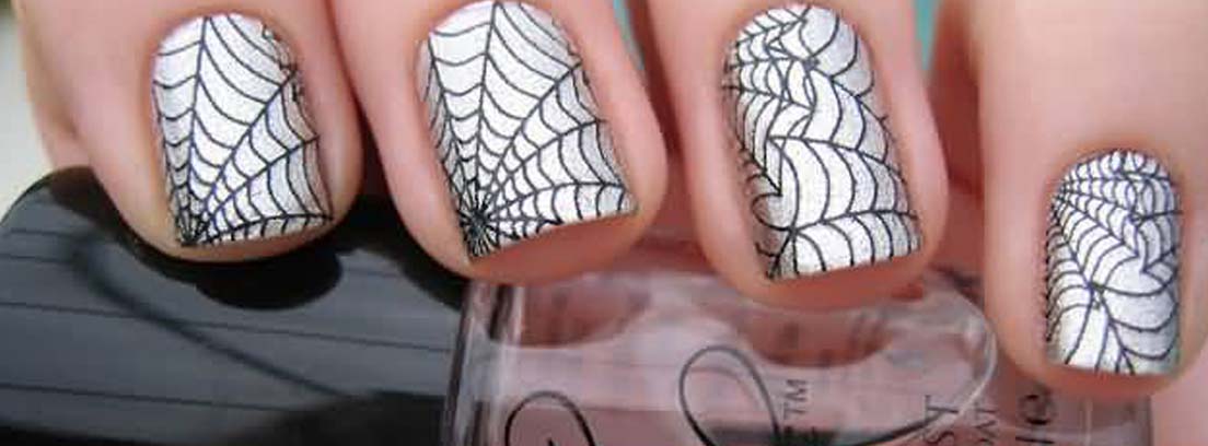 Uñas decoradas con esmalte plateado y dibujos de telarañas