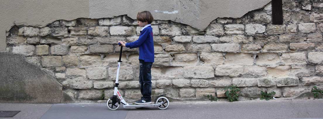 Niño sobre un patinete en una calle de París