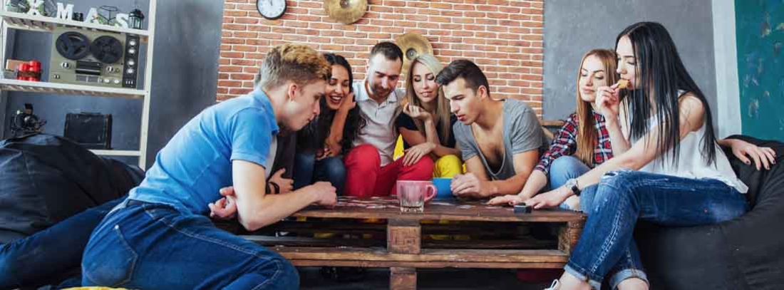 Jugar a juegos de mesa uno de los planes para el fin de semana amigos jugando en una mesa disfrutando de sus planes para el fin de semana