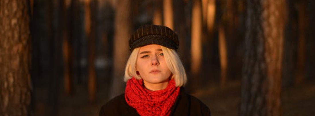 Mujer con bufanda tipo tubular roja en su cuello y con gorra negra.
