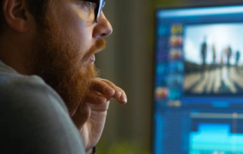 Hombre de perfil frente a una pantalla de ordenador con un editor de vídeos gratis