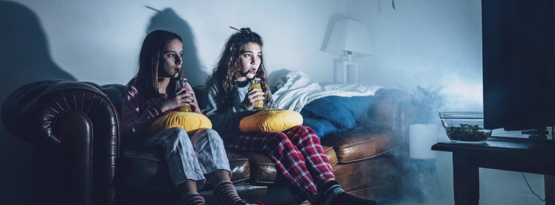 Dos chicas sentadas en un sofá viendo la televisión