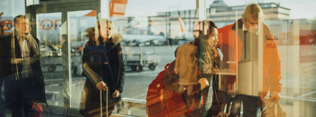 Personas con maletas y equipajes de mano caminando por el aeropuerto
