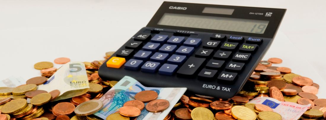 Calculadora sobre un montón de monedas y billetes de euro