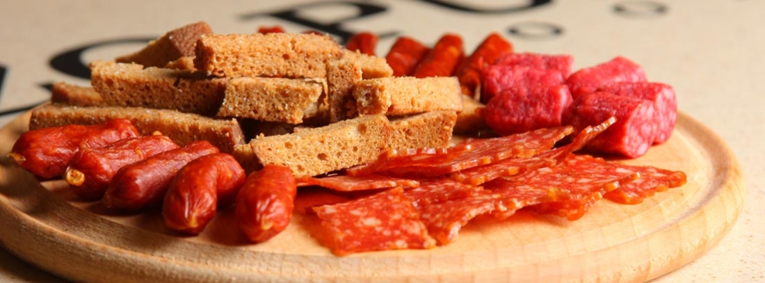 Plato de madera con embutidos y pan tostado, una forma de cmer gratis con una consumición