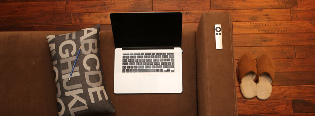 ¿Se puede tener Internet en casa sin teléfono fijo? - generacionYOUNG Vista cenital de un sofá con un ordenador portátil, un cojín y unas zapatillas