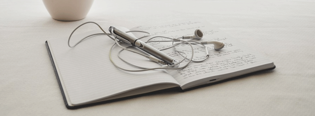 cuaderno sobre una mesa con unos auriculares