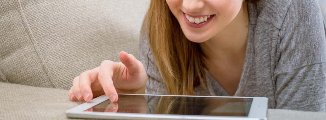 4G ilimitado para casa - generacionYOUNG Mujer mira su tableta tumbada en un sofá