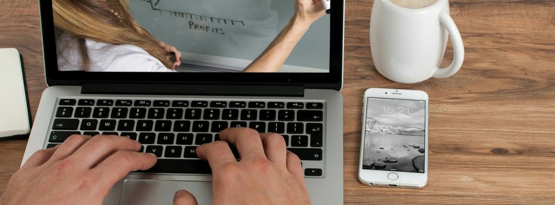 Cómo usar tu móvil como modem - generacionYOUNG Manos sobre teclado de portátil junto a un teléfono móvil.
