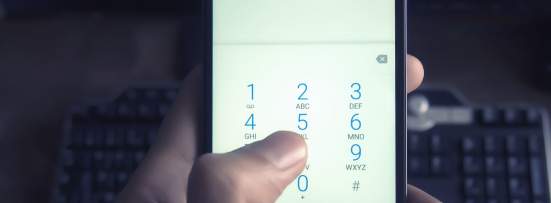 Mano sujeta móvil en la pantalla de marcación