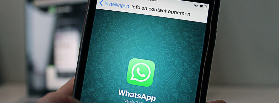 Mano sujeta móvil con pantalla de WhatsApp