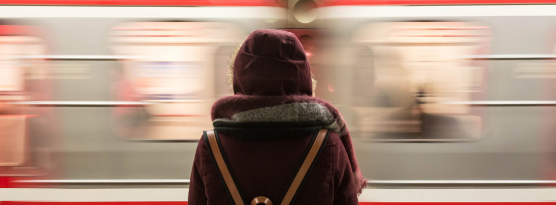 Persona de espaldas frente a un tren de Metro con efecto de velocidad