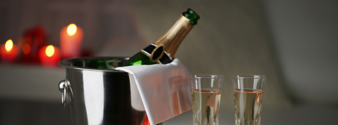 Botella de champán, copas y velas rojas