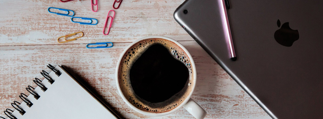 iPad con lápiz sobre él al lado de una taza de café
