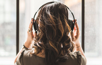 Mujer de espaldas con manos sobre cascos de música