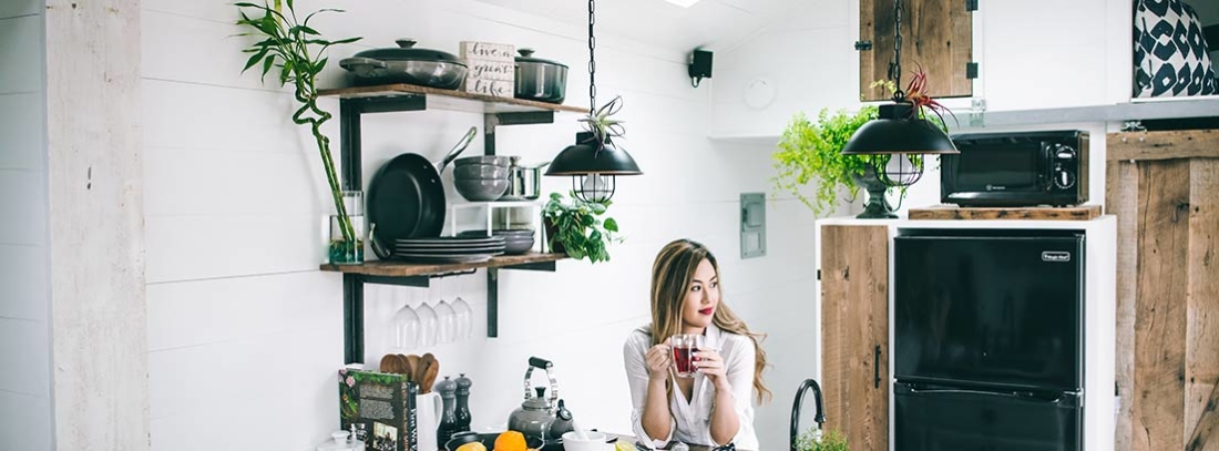 Mujer sentada en cocina de casa con taza entre las manos