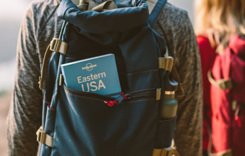 Hombre y mujer de espaldas con mochilas en un espacio natural.