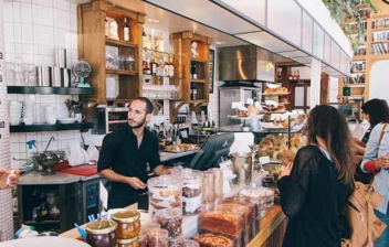 Vista general de bar con barra camareros de negro y personas en la barra