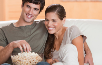 Pareja joven viendo una película y comiendo palomitas