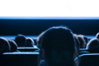 Varias personas sentadas de espaldas en una sala de cine a oscuras