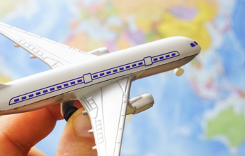 Mano sujetando un avión de juguete sobre un mapa del mundo