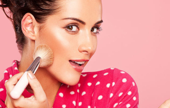 Mujer aplicando maquillaje con una brocha en su cara